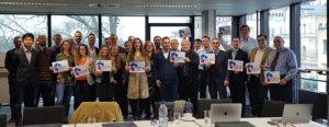 group photo of people in a seminar room holding the project logo